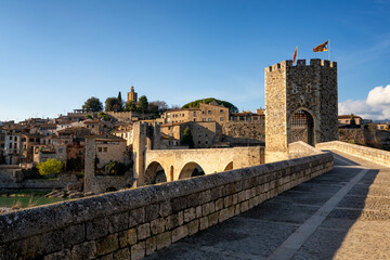 Wall Mural - Besalu historic medieval city with Catalonia flags on the stone bridge tower crossing El Fluvia river, in Spain