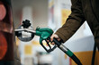Close-up of woman filling car fuel tank at gas pump.