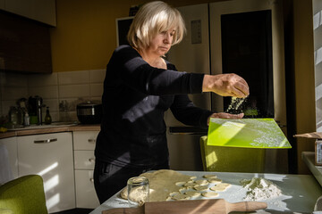 Housewife making dumplings with dough and mashed potato. The process of cooking ukrainian vareniki. Kitchen utensils, dough and handmade dumplings on the table