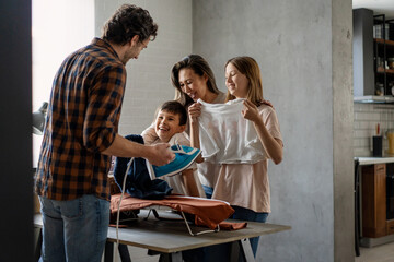 Wall Mural - Happy mixed race family doing together domestic chores, ironing, household together at home.