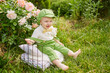 © яна винникова - A cute little boy is sitting in a beautiful flowering shrub in the park in summer and smiling sweetly