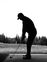 Silhouette Of A Man Holding His Driver As He Practices His Golf Swing At A Driving Range Facility During Off-season In Alberta Canada. Black And White