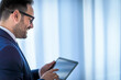 © Route77 - Close-up on a manager holding digital tablet standing in the office. concept of digital age. Businessman typing on the tablet computer