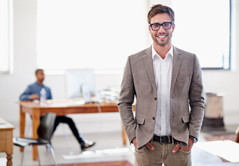 Wall Mural - Youll love this office. Portrait of a young man standing in an office with a coworker in the background.