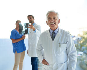 Aufkleber - Were in it together for the good of your health. Portrait of a mature doctor standing in a hospital with his colleagues in the background.