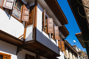 Close-up wall of a stone house with wooden windows and shutters. Old european architecture