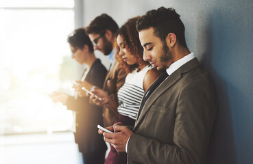 Poster - Online success is fueled by the profile you create. Cropped shot of businesspeople using their cellphones while standing in a row.