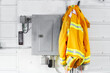 © kat7213 - A yellow adult firefighters coat hanging beside an electrical box on a tin wall