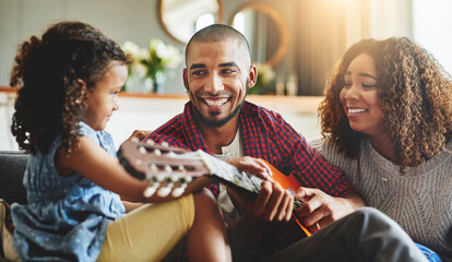 Sticker - Tuned into family time. Shot of an adorable little girl and her parents playing a guitar together on the sofa at home.