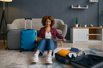 Wall Mural - Woman reading travel map surrounded with luggage