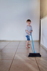 Wall Mural - Sweeping is my chore for the day. Portrait of an adorable little boy using a broom to sweep the floor at home.