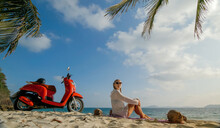 Scooter Road Trip. Woman Alone On Red Motorbike In White Clothes On Sand Beach By Ocean. One Girl Caucasian Tourist Walk Near Tropical Palm Tree, Sea. Asia Thailand Motorcycle Rent. Safety Helmet.