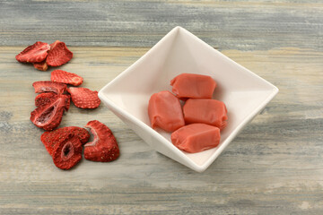 Wall Mural - Strawberry toffee pieces in white candy dish and freeze dried dehydrated strawberries on table