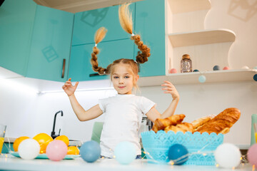 A little girl of 6-7 years old stands in the kitchen at the table and chooses a freshly baked bun. homemade baking