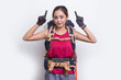 Young asian hiker woman with backpack pointing finger on empty space on white background
