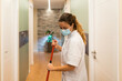 Cleaning woman using a face mask while cleaning the corridor of a Spa or health center.