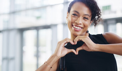 Poster - Doing what I love and loving what I do. Cropped shot of a young businesswoman showing a heart sign while walking through a modern office.