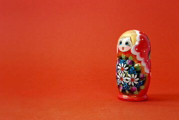 Closed nesting doll on red background with copy space.