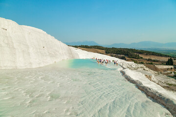 Wall Mural - Natural travertine pools and terraces in Pamukkale. Cotton castle in southwestern Turkey. Tourists walking and bathing in Natural travertine pools