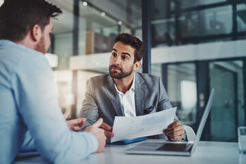 Poster - Statistical analysis that tell a story of success. Shot of two young businessmen using a laptop while going through paperwork together in a modern office.