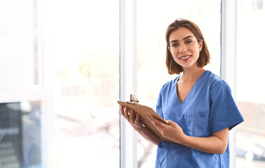 Aufkleber - Medicine is my life. Portrait of a cheerful young female doctor holding a clipboard while looking at the camera in a clinic.