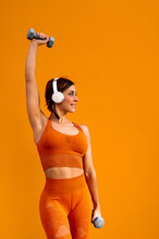 Alegre Mujer Deportista Con Unos Auriculares Haciendo Ejercicios Físicos Sobre Un Fondo De Color Naranja