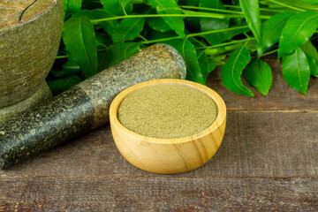 Wall Mural - Neem powder in wooden bowl with neem leaf and mortar and pestle on wooden background.