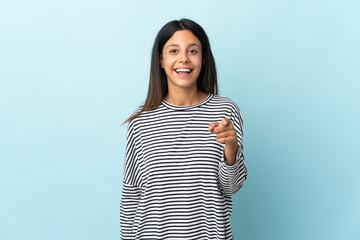 Poster - Caucasian girl isolated on blue background surprised and pointing front