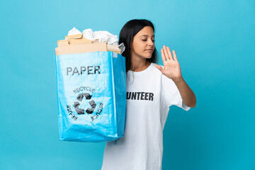 Poster - Young woman holding a recycling bag full of paper making stop gesture and disappointed