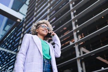 Confident cool black business woman talking on the phone outside a modern building. Young female professional on a call.