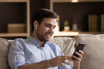 Wall Mural - smiling handsome young man in digital headset make video call on modern smartphone enjoy distant com