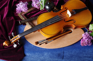 Canvas Print - Flowers in vases, violin, art palette and brushes on a table with a blue tablecloth.