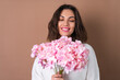 © Анастасия Каргаполов - A young woman with wavy voluminous hair on a beige background with bright pink lipstick lip gloss in a white sweater holds a bouquet of pink flowers