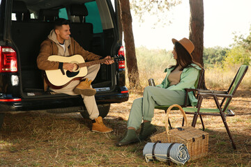 Wall Mural - Couple with guitar, picnic basket and chairs at camping site