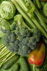 Wall Mural - bright fresh vegetables on green background flat lay top view, close-up shot. Seasoning for dish, spices for cooking, bell pepper, broccoli, cucumber, cabbage and other food. Creative layout