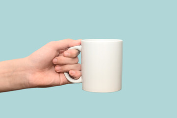 Close-up of a woman's hand holding an empty white mug. On a blue background.