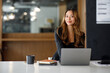 © David - Charming Asian businesswoman sitting in the office with a digital laptop computer. Excited Asian businesswoman raising hands to congratulate while working in a modern office,