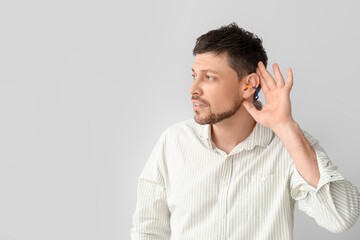 Canvas Print - Handsome man with ear plugs on light background