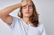 Young handsome man with long hair with hand head because of painful disease feeling unwell. Ache concept. headache. caucasian european guy posing isolated over white background. copy space