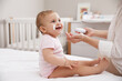 © New Africa - Mother applying moisturizing cream on her little baby at home, closeup