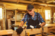 © bondvit - Portrait of a senior carpenter in uniform gluing wooden bars with hand pressures at the carpentry manufacturing