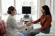 © pressmaster - Side view of female clinician and patient shaking hands in medical office while sitting in front of one another against ultrasound machine