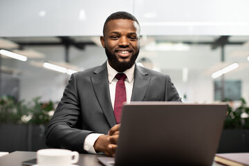 Handsome black businessman posing at workdesk in office