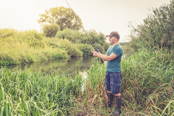 Wall Mural - Fisherman on the river at dawn in summer.