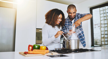 Aufkleber - Little seasoning never hurt anybody. Shot of a young couple cooking together at home.