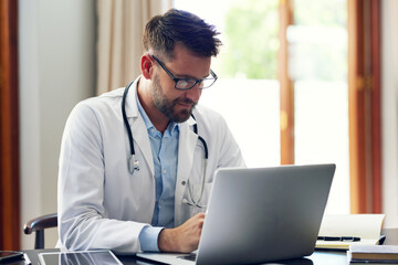 Poster - Updating his clients records. Cropped shot of a handsome male doctor working on his laptop while sitting in his office.