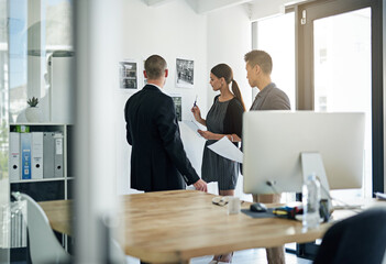 Poster - Going over their strategy. Cropped shot of three colleagues working in the office.