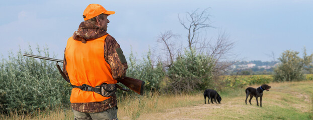 Hunter man in camouflage with a gun during the hunt in search of wild birds or game. Autumn hunting season.