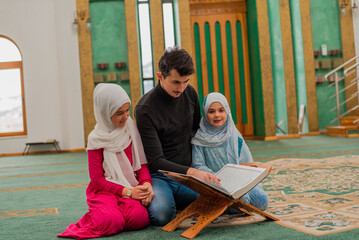 Wall Mural - Happy Muslim family reading a holy book Quran. Father teaching child daughter Islam religion. Top view of the group of people learning a holy book Quran in the mosque.