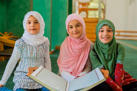 group of a children reading a holy book quran in the mosque. happy muslim family. muslim girls in hi